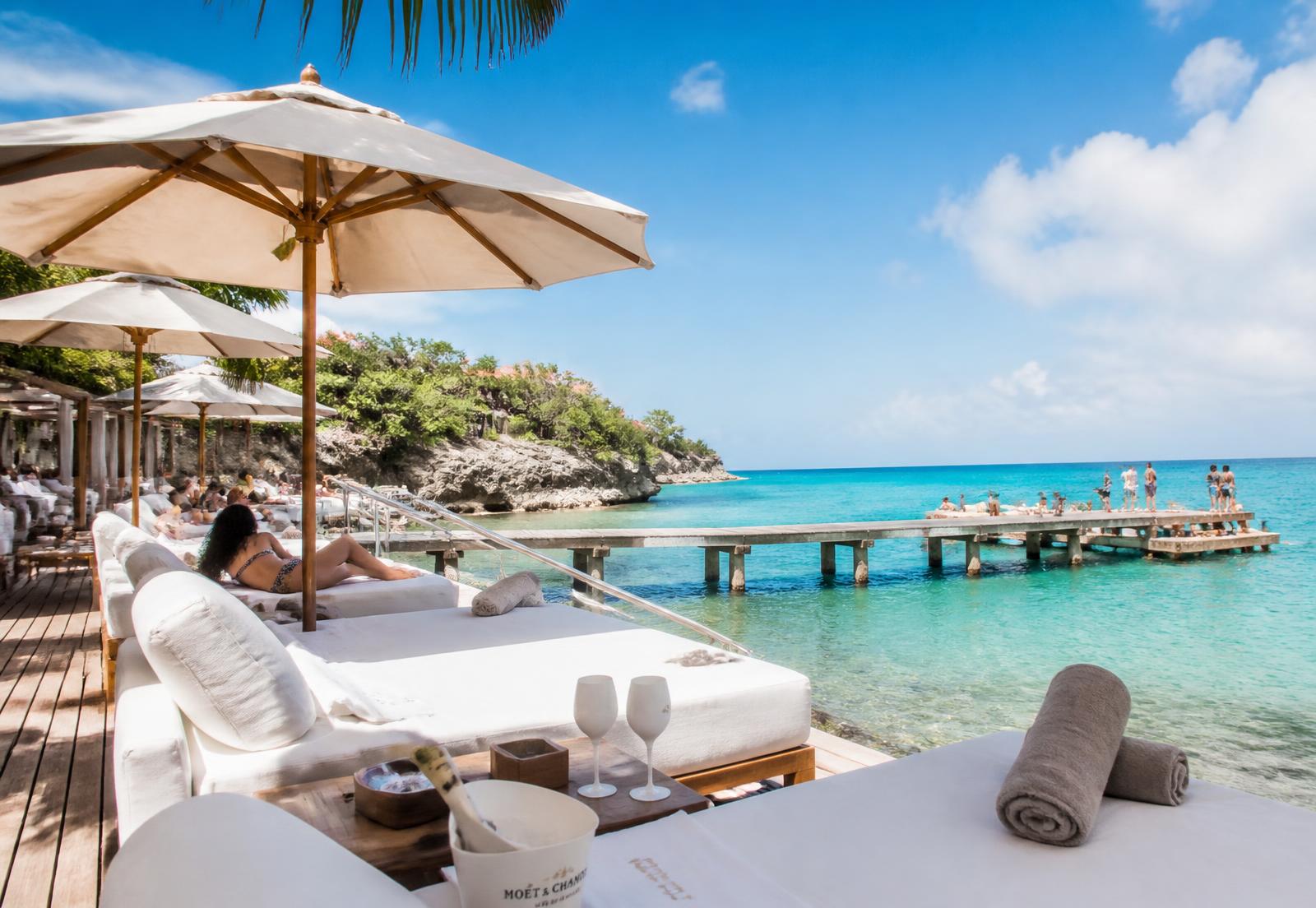 Ligbedden en steiger bij een luxe beachclub aan turquoise zee